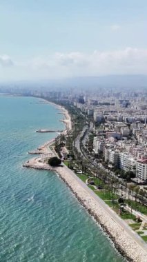Kıyı şehirlerinde beyaz binalar, sakin bir plaj ve uzaktaki görkemli dağlar sergilenir. Sakin mavi sular sakin bir atmosfer yaratarak manzarayı güzelleştirir.