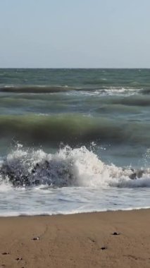 Tenha bir sahile çarpan turkuaz dalgalar sakin bir atmosfer yaratır. Açık mavi bir gökyüzü ve okyanusun rahatlatıcı sesi huzur ortamını güçlendirir.