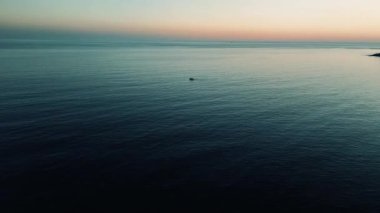 Altın saat, sakin bir denizin üzerindeki gökyüzünü boyar. Mersin, hindi kıyılarında huzur içinde yüzen küçük bir tekne huzurlu ve resimli bir deniz manzarası yaratır.