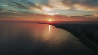 Göz kamaştırıcı gün batımı, Akdeniz 'in üzerinde sıcak bir parıltı yayarak kıyı şehrinin sahil şeridini aydınlatıyor. Canlı renkler huzurlu ve resimli bir akşam atmosferi yaratıyor.