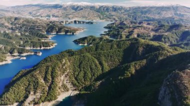 Kahramaras dağlık arazisinde yuva yapmış Kartalkaya baraj gölünü ortaya çıkaran hava manzarası, parlak güneş ışığı altında değişen renkler ve dinamik gölgeler sergiliyor.
