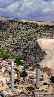 Bir tünel inşaatı ve bir vadide viyadük ilerlemesi, dağlık bir Türk manzarası arasında ağır makineler ve mühendislik becerileri sergiliyor.