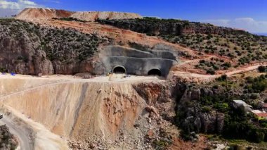 Dağlık tünelleri kazma, güçlü kazı makineleri ve engebeli Türk arazisinde hassas mühendislik teknikleri kullanmada usta inşaat ekibi.