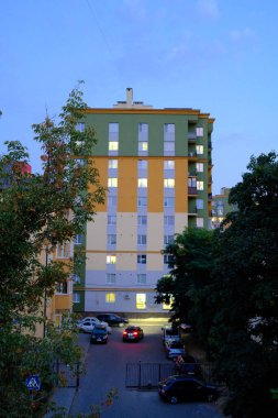 Ukrayna 'daki bir apartmanda, hava kararırken arabaların sokağa park etmesi gibi pencerelerinden süzülen parlak ışıklar görülüyor..