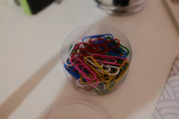 Birçok rengin ataçları bir masanın üzerindeki temiz plastik bir kabın içinde..