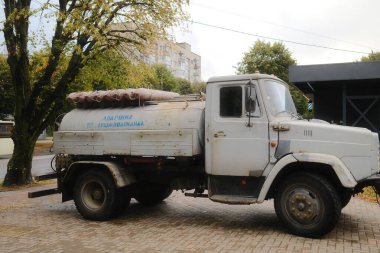 Üzerinde Lutskvodokanal yazan yıpranmış bir su tankı kamyonu, tuğlalı bir şehir caddesinde duruyor..