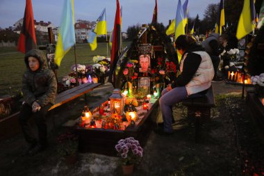 Lviv, Ukrayna, 1 Kasım 2022. Ukraynalılar, Lviv 'deki Lychakiv Mezarlığı' ndaki Azizler Günü ve Ruhlar Günü münasebetiyle Rusya ile savaşta ölen Ukraynalı askerlerin mezarlarını ziyaret ederken mum yakarlar. Rusya 24 Şubat 'ta Ukrayna' yı işgal etti