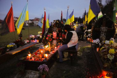 Lviv, Ukrayna, 1 Kasım 2022. Ukraynalılar, Lviv 'deki Lychakiv Mezarlığı' ndaki Azizler Günü ve Ruhlar Günü münasebetiyle Rusya ile savaşta ölen Ukraynalı askerlerin mezarlarını ziyaret ederken mum yakarlar. Rusya 24 Şubat 'ta Ukrayna' yı işgal etti