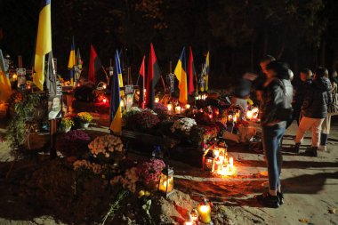 Lviv, Ukrayna, 1 Kasım 2022. Ukraynalılar, Lviv 'deki Lychakiv Mezarlığı' ndaki Azizler Günü ve Ruhlar Günü münasebetiyle Rusya ile savaşta ölen Ukraynalı askerlerin mezarlarını ziyaret ederken mum yakarlar. Rusya 24 Şubat 'ta Ukrayna' yı işgal etti