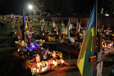 Lviv, Ukrayna, 1 Kasım 2022. Ukraynalılar, Lviv 'deki Lychakiv Mezarlığı' ndaki Azizler Günü ve Ruhlar Günü münasebetiyle Rusya ile savaşta ölen Ukraynalı askerlerin mezarlarını ziyaret ederken mum yakarlar. Rusya 24 Şubat 'ta Ukrayna' yı işgal etti
