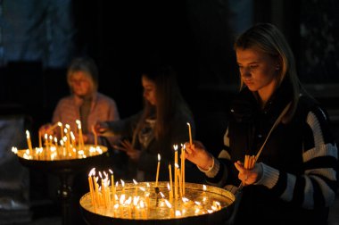 Lviv, Ukrayna 15 Nisan 2023. Aziz Peter ve Paul Garrison Kilisesi 'nde İsa' nın dirilişini kutlamak için düzenlenen yemek sepetleri seremonisinden önce bir kadın mum yakıyor.