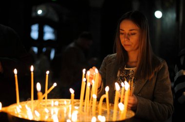 Lviv, Ukrayna 15 Nisan 2023. Aziz Peter ve Paul Garrison Kilisesi 'nde İsa' nın dirilişini kutlamak için düzenlenen yemek sepetleri seremonisinden önce bir kadın mum yakıyor.