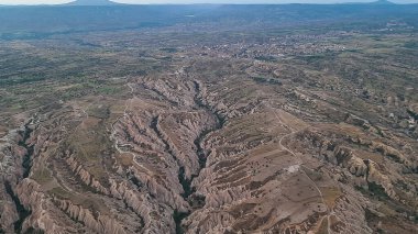 Kapadokya Türkiye 'de kayaların üzerinde uçan sıcak hava balonu. Uchisar köyündeki mağara evi., 