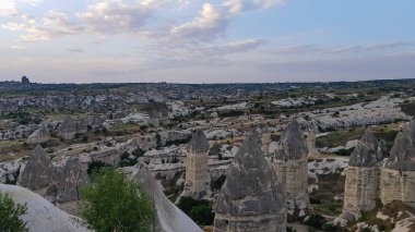 Kapadokya Türkiye 'de kayaların üzerinde uçan sıcak hava balonu. Uchisar köyündeki mağara evi., 