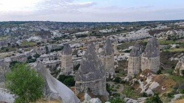 Kapadokya Türkiye 'de kayaların üzerinde uçan sıcak hava balonu. Uchisar köyündeki mağara evi., 