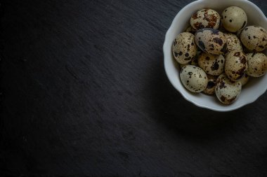 Siyah taşın üzerinde beyaz tabakta taze bıldırcın yumurtaları, seçici bir odak noktası. Yüksek kalite fotoğraf