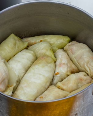 Kadınlar masada dururken lahana rulosu pişirir ve tencereye koyarlar. Yüksek kalite fotoğraf