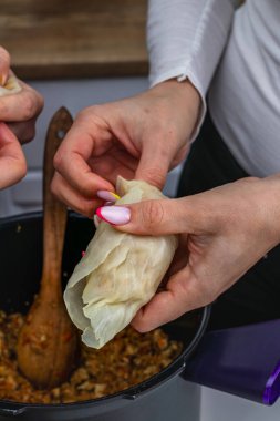 Kadınlar masada dururken lahana rulosu pişirir ve tencereye koyarlar. Yüksek kalite fotoğraf