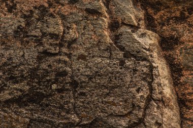 Koyu kırmızı, kahverengi, çatlaklı kaya dokusu. Yakın çekim. Sert dağ yüzeyi. Tasarım için taş granit arka plan. Doğalcı