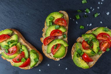 Avokado tostu domates ve yeşil soğanlı bir dilim havuçlu yüksek kaliteli fotoğraf.