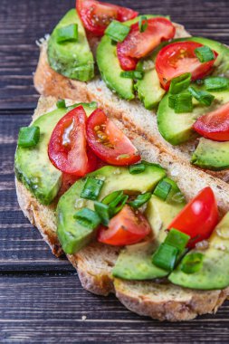 Avokado tostu domates ve yeşil soğanlı bir dilim havuçlu yüksek kaliteli fotoğraf.