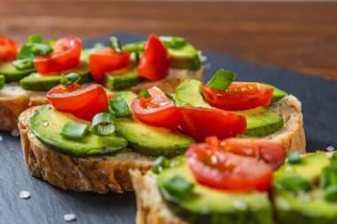 Avokado tostu domates ve yeşil soğanlı bir dilim havuçlu yüksek kaliteli fotoğraf.