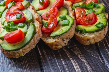 Avokado tostu domates ve yeşil soğanlı bir dilim havuçlu yüksek kaliteli fotoğraf.