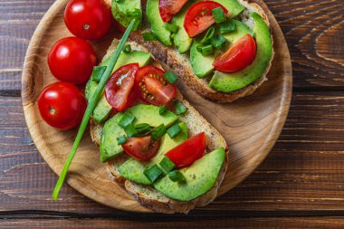 Avokado tostu domates ve yeşil soğanlı bir dilim havuçlu yüksek kaliteli fotoğraf.