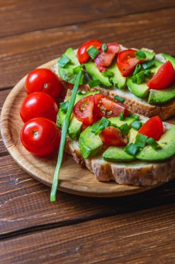 Avokado tostu domates ve yeşil soğanlı bir dilim havuçlu yüksek kaliteli fotoğraf.