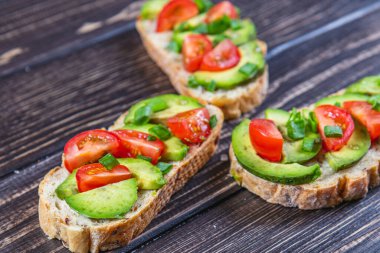 Avokado tostu domates ve yeşil soğanlı bir dilim havuçlu yüksek kaliteli fotoğraf.