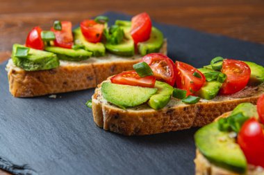 Avokado tostu domates ve yeşil soğanlı bir dilim havuçlu yüksek kaliteli fotoğraf.