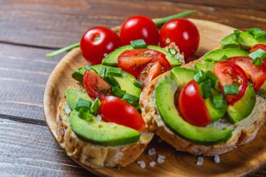 Avokado tostu domates ve yeşil soğanlı bir dilim havuçlu yüksek kaliteli fotoğraf.