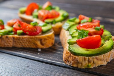 Avokado tostu domates ve yeşil soğanlı bir dilim havuçlu yüksek kaliteli fotoğraf.