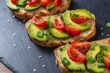 Avokado tostu domates ve yeşil soğanlı bir dilim havuçlu yüksek kaliteli fotoğraf.