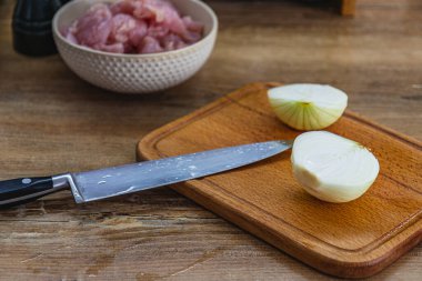 Bir tahtada iki parçaya ayrılmış soğan ve orta kalitede bir bıçak..