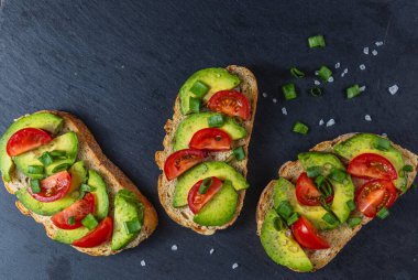 Avokado tostu domates ve yeşil soğanlı bir dilim havuçlu yüksek kaliteli fotoğraf.