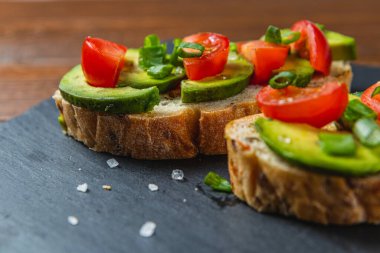 Avokado tostu domates ve yeşil soğanlı bir dilim havuçlu yüksek kaliteli fotoğraf.
