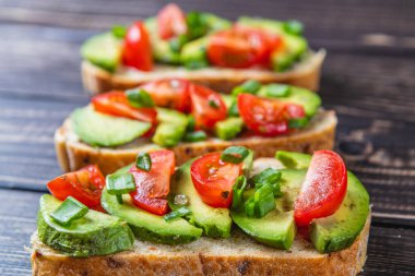 Avokado tostu domates ve yeşil soğanlı bir dilim havuçlu yüksek kaliteli fotoğraf.