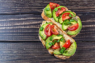 Avokado tostu domates ve yeşil soğanlı bir dilim havuçlu yüksek kaliteli fotoğraf.