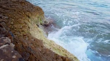 Huzurlu Kıyı Suları 'nda Rocky Shoreline ve Tranquil' in oynadığı Dalgalar görülüyor. Yüksek kalite 4k görüntü