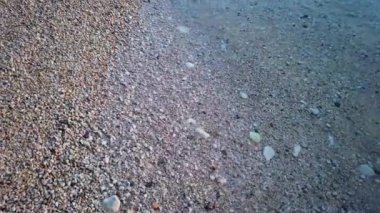 Çakıl taşlarıyla bezenmiş sakin bir sahil, baş döndürücü bir günbatımı ile güzelce süslenmiş. Yüksek kalite 4k görüntü