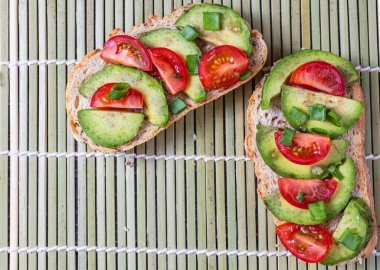 Avokado tostu domates ve yeşil soğanlı bir dilim havuçlu yüksek kaliteli fotoğraf.