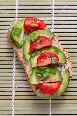 Avokado tostu domates ve yeşil soğanlı bir dilim havuçlu yüksek kaliteli fotoğraf.
