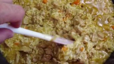 Bir adam tavada sebzeli pilav ve kıymalı dana eti pişirir. Yüksek kaliteli FullHD görüntüler