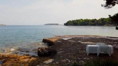 Huzurlu Kıyı Suları 'nda Rocky Shoreline ve Tranquil' in oynadığı Dalgalar görülüyor. Yüksek kalite 4k görüntü