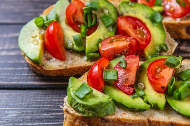 Avokado tostu domates ve yeşil soğanlı bir dilim havuçlu yüksek kaliteli fotoğraf.