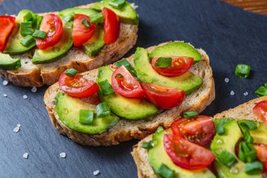Avokado tostu domates ve yeşil soğanlı bir dilim havuçlu yüksek kaliteli fotoğraf.