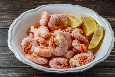 Kaynamış kral karidesleri derin kasede, limonlu, koyu masa manzaralı yüksek kaliteli fotoğraf.