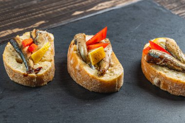 Masadaki taş tahtada üç balık sandviçi.