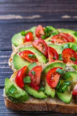 Avokado tostu domates ve yeşil soğanlı bir dilim havuçlu yüksek kaliteli fotoğraf.